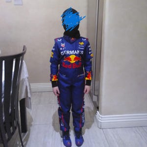 Puede incluir: Un mono de carreras azul marino con detalles rojos y amarillos, con el logotipo de Red Bull y el texto "GERMAN'S". El mono tiene varios logotipos de patrocinadores y se usa con zapatos azules a juego.