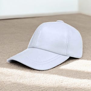 May include: A white baseball cap with a curved peak. The cap features a structured design with stitched seams and a button on top. The hat is made of a smooth, solid-coloured material.