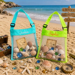 May include: Two mesh beach bags with adjustable straps, one turquoise and one lime green. The turquoise bag is embroidered with the name James, and the lime green bag is embroidered with the name Sophia. Both bags contain seashells and treasure maps.