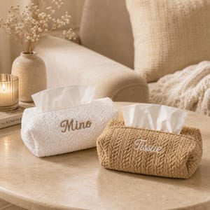 Può includere: Due copertine rettangolari per scatole di fazzoletti con un motivo a maglia intrecciata testurizzato. La copertina bianca presenta il nome Mino ricamato in marrone, mentre quella beige presenta la parola Tissue ricamata in bianco.