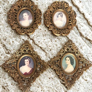 May include: Four antique gold-colored frames with oval portraits of women. Two frames are round with floral designs, and two are diamond-shaped. The portraits feature women in period clothing, with soft colors and delicate details.