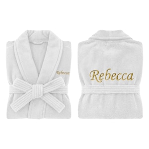 Könnte beinhalten: Zwei Ansichten eines weißen Frottee-Bademantels mit dem Namen "Rebecca" in goldfarbenem Faden gestickt. Der Bademantel hat einen Schalkragen, einen Taillenriemen und der Name ist auf Brust und Rücken gestickt.
