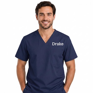 May include: Navy blue scrub top with a V-neck and a chest pocket. The name "Drake" is embroidered in white on the left chest. The short-sleeved top is made of a soft, comfortable material.