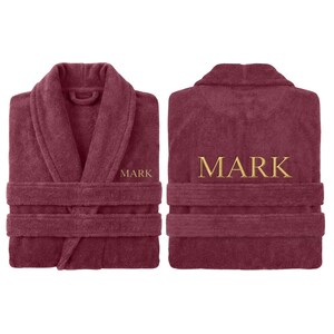 May include: A burgundy terry cloth robe with a shawl collar and belt loops. The name "MARK" is embroidered in gold thread on the front and back of the robe. The robe is displayed from the front and back.