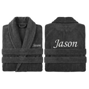 May include: Charcoal gray terry cloth bathrobe with the name "Jason" embroidered in white on the front and back. The robe has a shawl collar, two front pockets, and a matching belt. The robe is folded neatly.