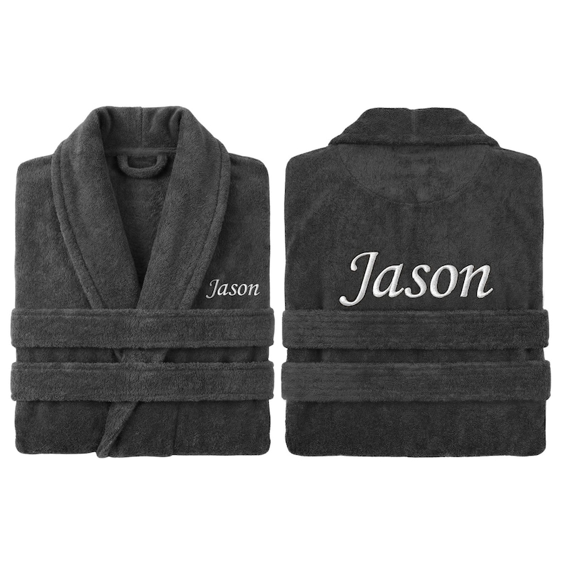 May include: Charcoal gray terry cloth bathrobe with the name "Jason" embroidered in white on the front and back. The robe has a shawl collar, two front pockets, and a matching belt. The robe is folded neatly.