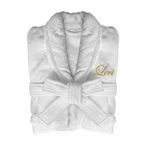 Puede incluir: Bata de ba&ntilde;o blanca de rizo con cuello chal y cintur&oacute;n adjunto. La palabra "Levi" est&aacute; bordada en oro en el pecho. La bata est&aacute; doblada cuidadosamente, mostrando la textura de la tela.