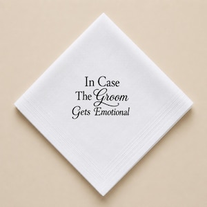 Può includere: Fazzoletto bianco con la scritta "In Case The Groom Gets Emotional" in corsivo nero. Il fazzoletto è piegato a forma di diamante con un bordo dettagliato.
