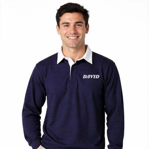 Può includere: Camicia da rugby blu navy a maniche lunghe con colletto bianco e il nome "DAVID" stampato in bianco. La camicia ha un classico colletto a polo e una paramontura con bottoni. Realizzata in un materiale morbido e confortevole.