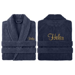 May include: Navy blue terry cloth bathrobe with the name "Helen" embroidered in gold script on the front and back. The robe features a shawl collar, two front pockets, and a matching belt. The plush fabric is visible in a front and back view.