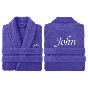 May include: A purple terry cloth robe with the name "John" embroidered on the front and back. The robe has a shawl collar, a waist tie, and two front pockets. The robe is displayed from the front and back.