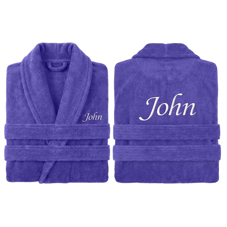May include: A purple terry cloth robe with the name "John" embroidered on the front and back. The robe has a shawl collar, a waist tie, and two front pockets. The robe is displayed from the front and back.
