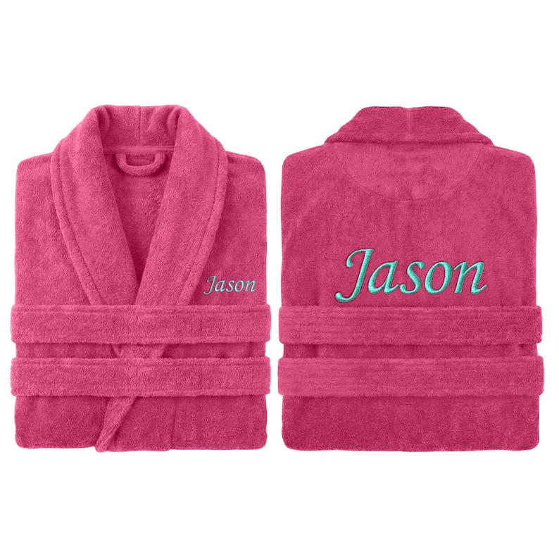 May include: A magenta terry cloth robe with the name "Jason" embroidered in teal on the front and back. The robe has a shawl collar, a waist tie, and two front pockets. The robe is displayed from the front and back.
