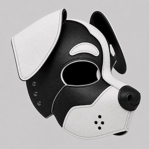 Pode incluir: Um capuz em forma de cão preto e branco com acabamento texturizado, orelhas grandes e caídas, uma abertura central para os olhos e uma zona de focinho com quatro pequenos orifícios de ventilação. Inclui rebites metálicos escuros e debrum branco.