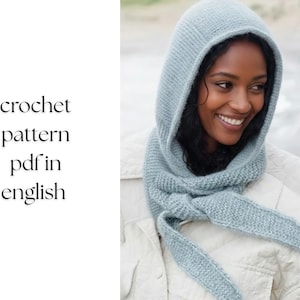 Könnte beinhalten: Hellblaues Häkel-Hoodie- und Schal-Set. Die Kapuze ist hochgezogen und rahmt das Gesicht ein. Der Schal ist am Hals geknotet. Der Text "crochet pattern pdf in english" befindet sich links.