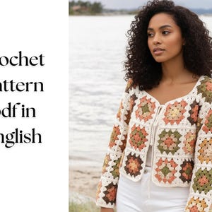 Peut inclure: Un cardigan au crochet avec des carrés granny de couleur crème, orange et vert. Le cardigan est ouvert sur le devant et a des manches longues. Le texte à gauche indique "crochet pattern pdf in english".