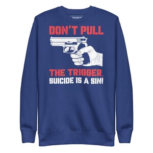 May include: A navy blue sweatshirt with the text "DON'T PULL THE TRIGGER, SUICIDE IS A SIN!" in red and white. The graphic features a silver handgun and a white hand holding it.