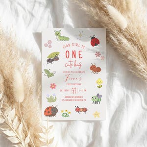 May include: A white invitation card with the text "OUR GIRL IS ONE cute bug" in red. The card features illustrations of various bugs and flowers. The invitation is for Fiona's first birthday, scheduled for March 21st, 1-4 PM.