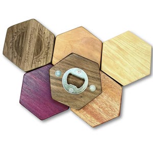May include: A selection of hexagonal wooden bottle openers and coasters in diverse wood shades. One opener has a silver bottle opener fixed to a dark wood hexagon. The top left hexagon has the text "SEAWoodworking".