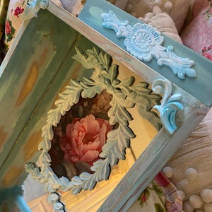 A distressed multi aqua wall shelf shadow box, rose floral in center in a scroll appliqué, bathroom, bedroom wall shelf.
