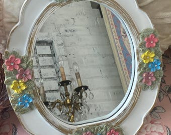 A shabby accent wall mirror, a floral design with raised flowers, crystal center