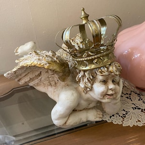 Resting large cherub with a gold oversized crown, day dreaming angel