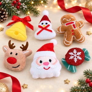 May include: A collection of six plush Christmas ornaments including a yellow bell with a red bow, a snowman, a gingerbread person, a reindeer head, a Santa Claus face, and a red candy shape with a white snowflake, all featuring embroidered details.