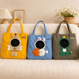 May include: Three canvas tote bags in yellow, blue, and olive green. Each bag features a plush animal character with a circular cutout and an embroidered name: Milo on the yellow bee bag, Luna on the blue rabbit bag, and Coco on the green dinosaur bag.
