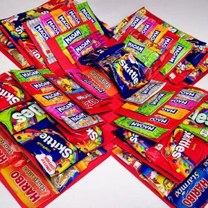 May include: A vibrant display of assorted sweets, such as Skittles, Haribo, and Maoam, presented on a red base. The image highlights a selection of popular confectionery brands, ideal for a gift or personal enjoyment.