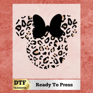 May include: A graphic transfer featuring a mouse-shaped silhouette with a leopard print pattern in black and tan, topped with a solid black bow. Below the graphic, a rectangular label displays the text DTF TRANSFER Ready To Press.