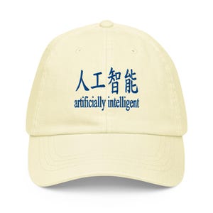 Könnte beinhalten: Eine cremefarbene Baseballkappe mit blauer Stickerei auf der Vorderseite. Die Stickerei zeigt die chinesischen Schriftzeichen für künstliche Intelligenz über dem englischen Text "artificially intelligent" in einer Serifenschrift. Gebogener Schirm.