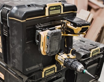 Pode incluir: Caixas de ferramentas pretas e amarelas DEWALT ToughSystem 2.0 empilhadas com uma furadeira sem fio amarela e preta. As caixas de ferramentas têm detalhes amarelos e fechos de metal. Uma bateria está conectada à furadeira.