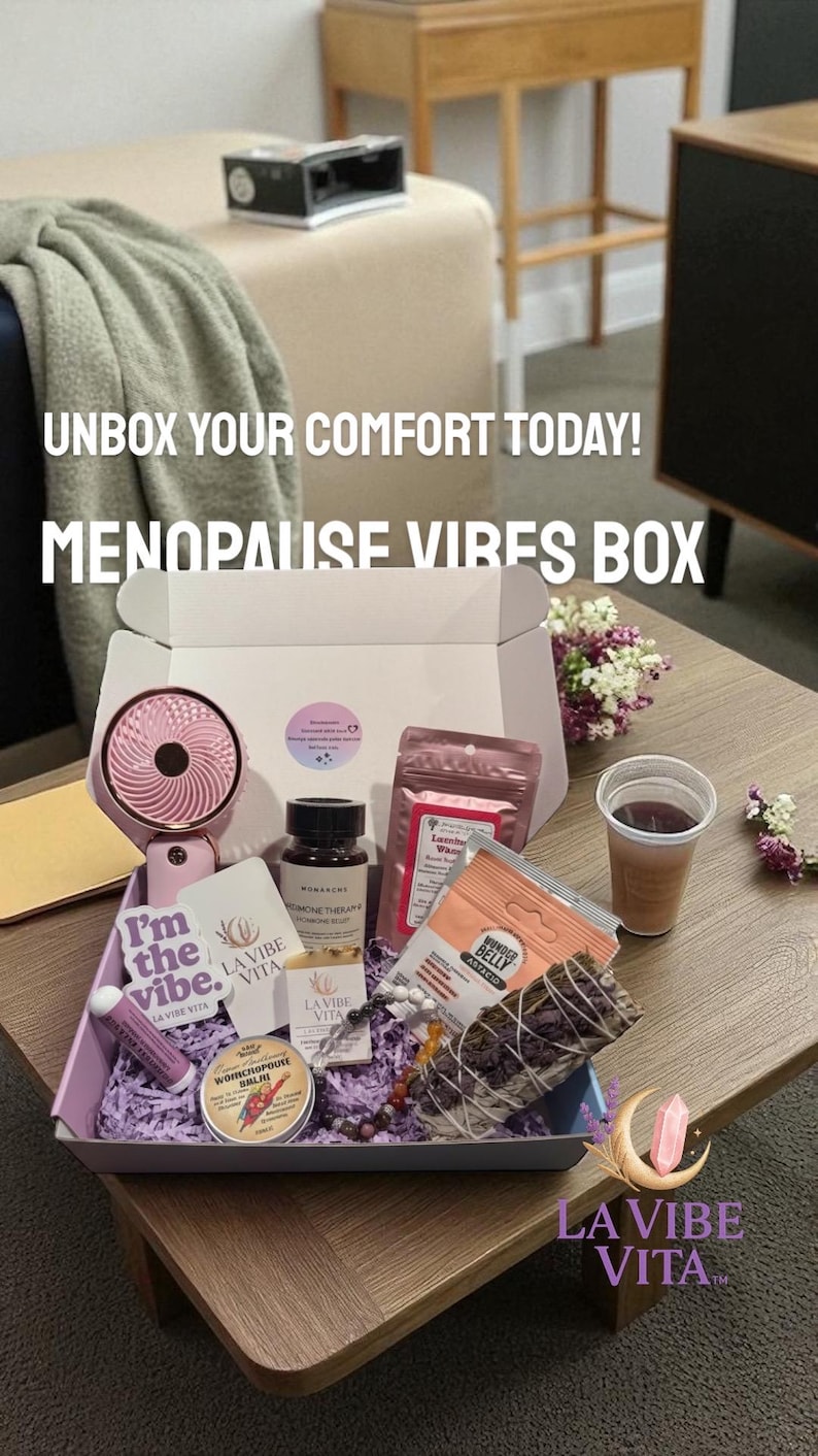 May include: A box labeled "MENOPAUSE VIBES BOX" filled with self-care items. Includes a pink fan, skincare products, tea, and a sage bundle. The box is on a table with the text "UNBOX YOUR COMFORT TODAY!" and "LA VIBE VITA" branding.