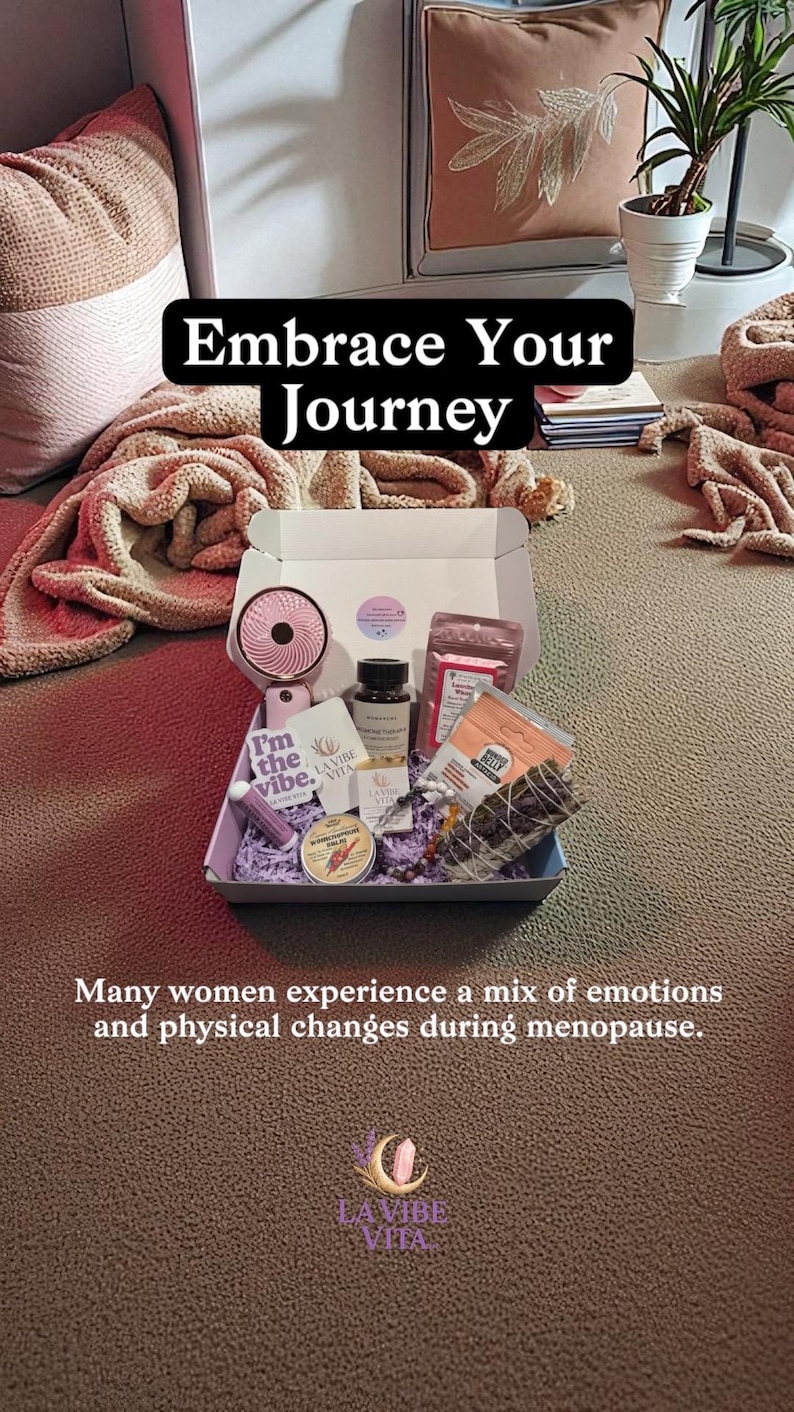 May include: An open gift box filled with self-care items, including a small fan, skincare products, and a candle. The box is on a brown surface, with text that reads "Embrace Your Journey" and "I'm the vibe."