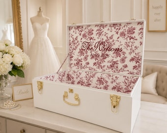 May include: A white rectangular wooden keepsake box with gold-toned metal latches and a handle. The interior lid and base feature a burgundy floral toile pattern. The text "The Wilsons" and "10.09.2026" is printed in burgundy on the inner lid.