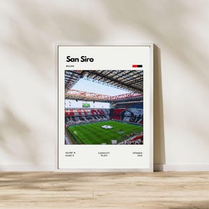 Könnte beinhalten: Gerahmter Druck des San Siro-Stadions in Mailand. Das Bild zeigt das Innere des Stadions mit einem grünen Spielfeld und Sitzbereichen in Rot, Schwarz und Weiß. Der Text oben lautet "San Siro, Milan". Zusätzlicher Text enthält Koordinaten, Kapazität und das Jahr 1926.