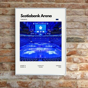 Puede incluir: Un póster enmarcado con una fotografía en tonos azules del interior del Scotiabank Arena en Toronto. La imagen muestra la pista de hielo, los asientos y las pantallas. El póster incluye el nombre del estadio, la ubicación, la capacidad y el año de apertura. La capacidad es de 19.800.