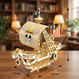 Puede incluir: Maqueta de barco de madera con temática pirata, con un diseño de calavera y huesos cruzados en la vela y las banderas. El barco mide 14,2 cm de largo, 6,1 cm de ancho y 13,5 cm de alto. El modelo es de madera clara.