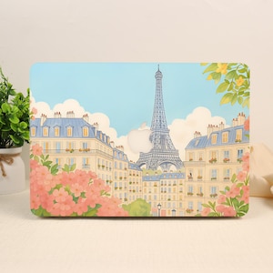 May include: A laptop hard shell case featuring a colorful illustration of the Eiffel Tower surrounded by Parisian buildings, blue sky with white clouds, and clusters of pink flowers in the foreground, with a central cutout for an Apple logo.