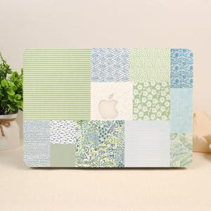 May include: A laptop skin featuring a patchwork design of various patterns in shades of green, blue, and white. The rectangular grid includes stripes, floral motifs, dots, and botanical prints, with a central cutout revealing an Apple logo.