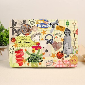 May include: A laptop skin featuring a grid pattern background covered in various stickers including a rabbit, a strawberry stack, a megaphone, headphones, a child in sunglasses, a ladybug, and text like Focus on Growth and one day at a time.