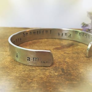 May include: Silver bracelet with the words "I am... smart, beautiful, kind, unique" engraved on it.