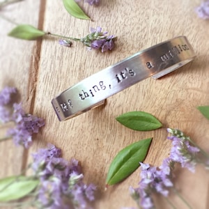May include: Silver bracelet with the words "The thing, it's a million"