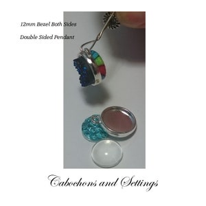 May include: Two 12mm double-sided pendant bezels with a silver finish. One bezel is filled with a blue and green cabochon, the other is empty. The bezels are shown with a jump ring attached.