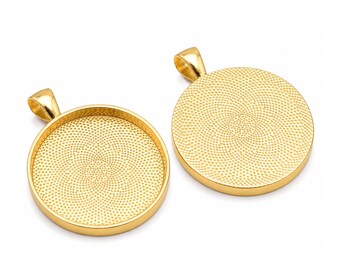 May include: Two gold-colored pendant trays with a circular design. Each pendant has a loop at the top for a chain. The trays have a textured interior, perfect for crafting custom jewelry. The pendants are displayed on a white background.