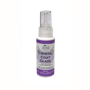 Op de afbeelding: Een witte plastic spuitfles van Quilled Creations Crystal Coat Glaze met een doorzichtige dop. Het etiket is paars en wit met de tekst Crystal Coat Glaze, Clear, Glossy Finish, Bonds & Protects Paper Art en 59 ml erop gedrukt.