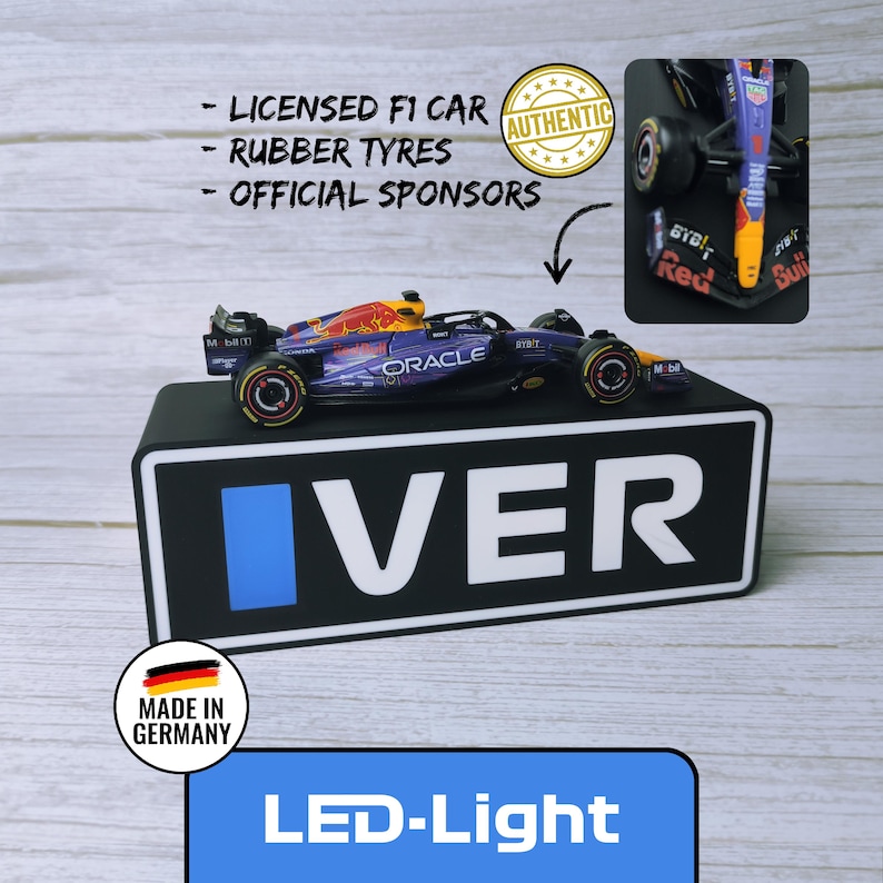May include: A miniature Formula 1 race car with a blue and red design, featuring sponsor logos and the word "ORACLE". The car sits on a black base with the word "IVER" and a blue rectangle. The image includes text that says "LED-Light".