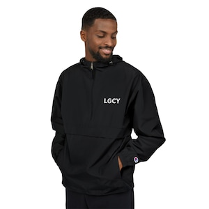 Könnte beinhalten: Schwarze Anorakjacke mit halbem Reißverschluss und Kapuze. Auf der Brust steht in Weiß "LGCY" und auf dem linken Ärmel ein Champion-Logo. Das Model trägt die Jacke.