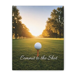 May include: A white golf ball sits on an orange tee in the center of a green grass fairway. In the background, rows of trees line the course under a bright sunset sky. The text "Commit to the Shot" is printed in white script at the bottom.