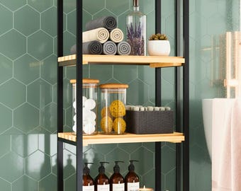 May include: A black metal and wood bathroom shelf unit filled with toiletries and accessories. The shelves hold rolled towels, glass jars, bottles of shampoo and conditioner, and decorative items like candles and a small plant.